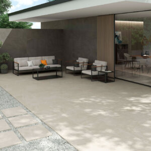 STN-AMB-BELLEVUE-2OUT-IVORY-60X60X2-STONE-60X120 Patio moderno con pavimento cerámico claro, muro oscuro, mobiliario minimalista y losas sobre grava