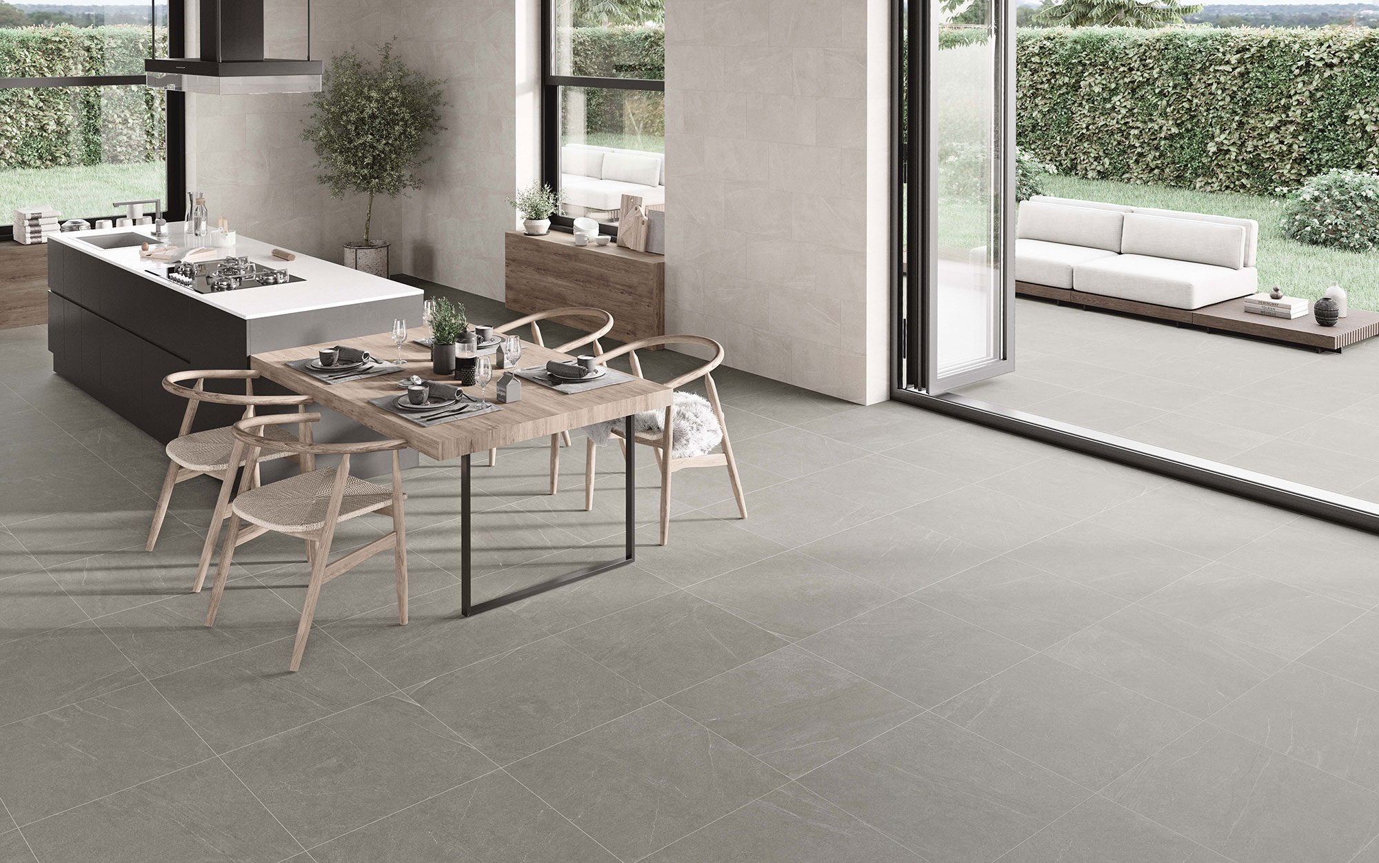 STN-AMB-BELLEVUE-INOUT-GREY-60X60_-IVORY-30X60-(SIMULADO) Cocina abierta con suelo cerámico gris, revestimiento mural, isla y comedor junto al jardín