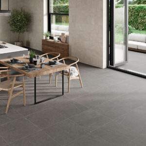 STN-AMB-BELLEVUE-INOUT-STONE-60X60_-IVORY-30X60 Cocina abierta con pavimento cerámico gris, revestimiento mural claro y terraza contigua