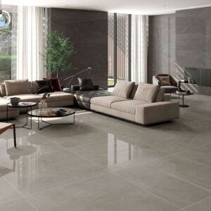 STN-AMB-BELLEVUE-PULIDO-GRAPHITE-60X120+GREY-120X120 Salón contemporáneo con pavimento cerámico gris pulido y sofás beige junto a ventanal
