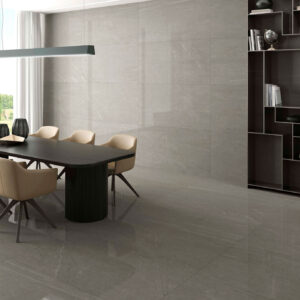 STN-AMB-BELLEVUE-STONE-PULIDO-60X120 Sala de exposición con mesa y sillas sobre gran pavimento y revestimiento cerámico gris