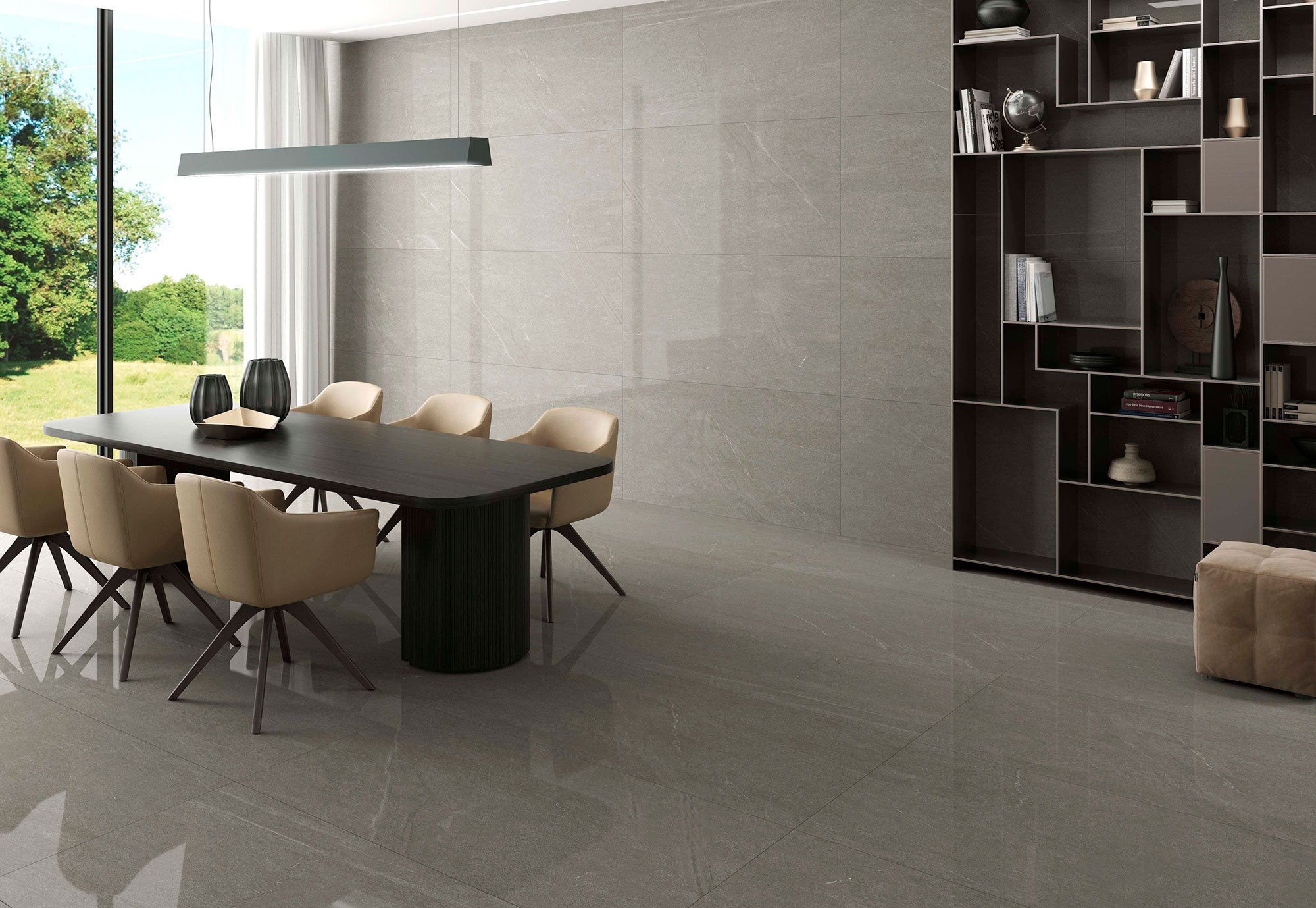 STN-AMB-BELLEVUE-STONE-PULIDO-60X120 Sala de exposición con mesa y sillas sobre gran pavimento y revestimiento cerámico gris