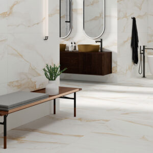 STN-AMB-CAMILE-GOLD-SATINADO-60X120 Baño con azulejos grandes efecto mármol blanco y vetas doradas, lavabo y bañera.