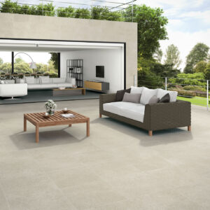 STN-AMB-HOMESTONE-ARGENT-2OUT-60X60-30X60-(SIMULADO) Terraza con pavimento cerámico gris claro, sofás de mimbre y mesa baja de madera