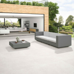 STN-AMB-HOMESTONE-PEARL-100x100 Terraza moderna con pavimento cerámico claro, sofás grises y salón abierto al jardín