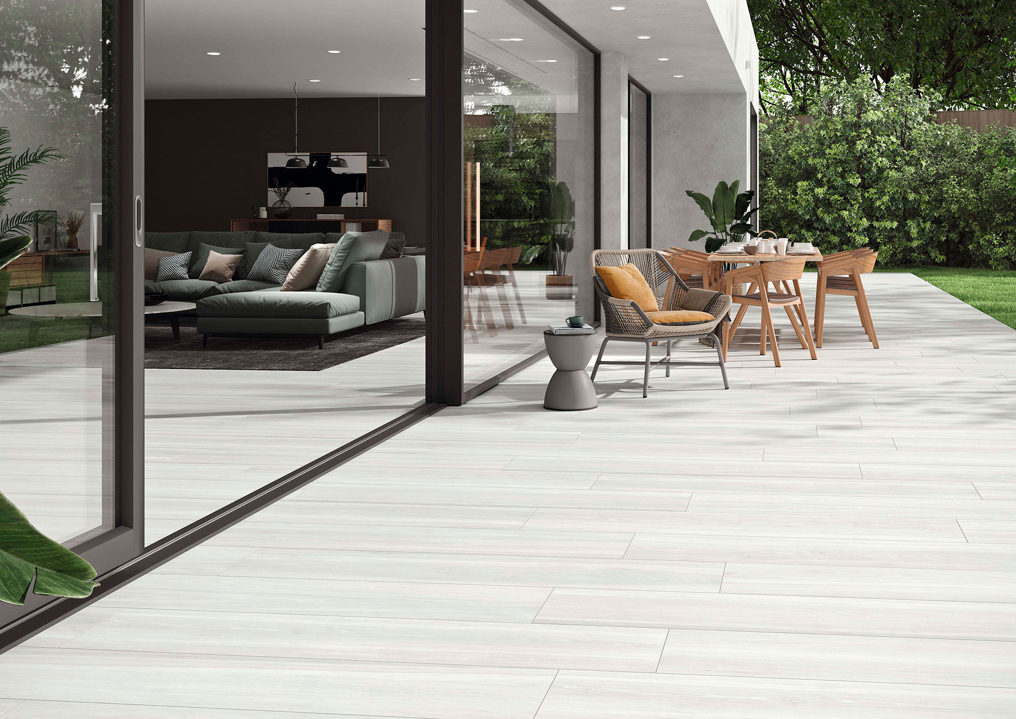 Terraza con pavimento cerámico efecto madera claro, mobiliario exterior y salón acristalado