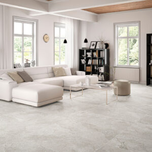 STN-AMB-ROCKSTONE-PEARL-60x120-CMYK-SIMULACION Salón moderno con sofá blanco y suelo de grandes baldosas cerámicas efecto piedra.