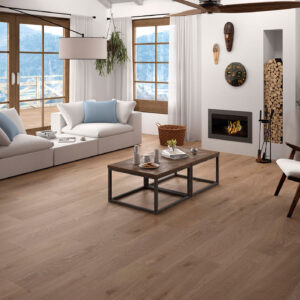 Salón con pavimento cerámico efecto madera, sofá blanco, chimenea y ventanales a la montaña