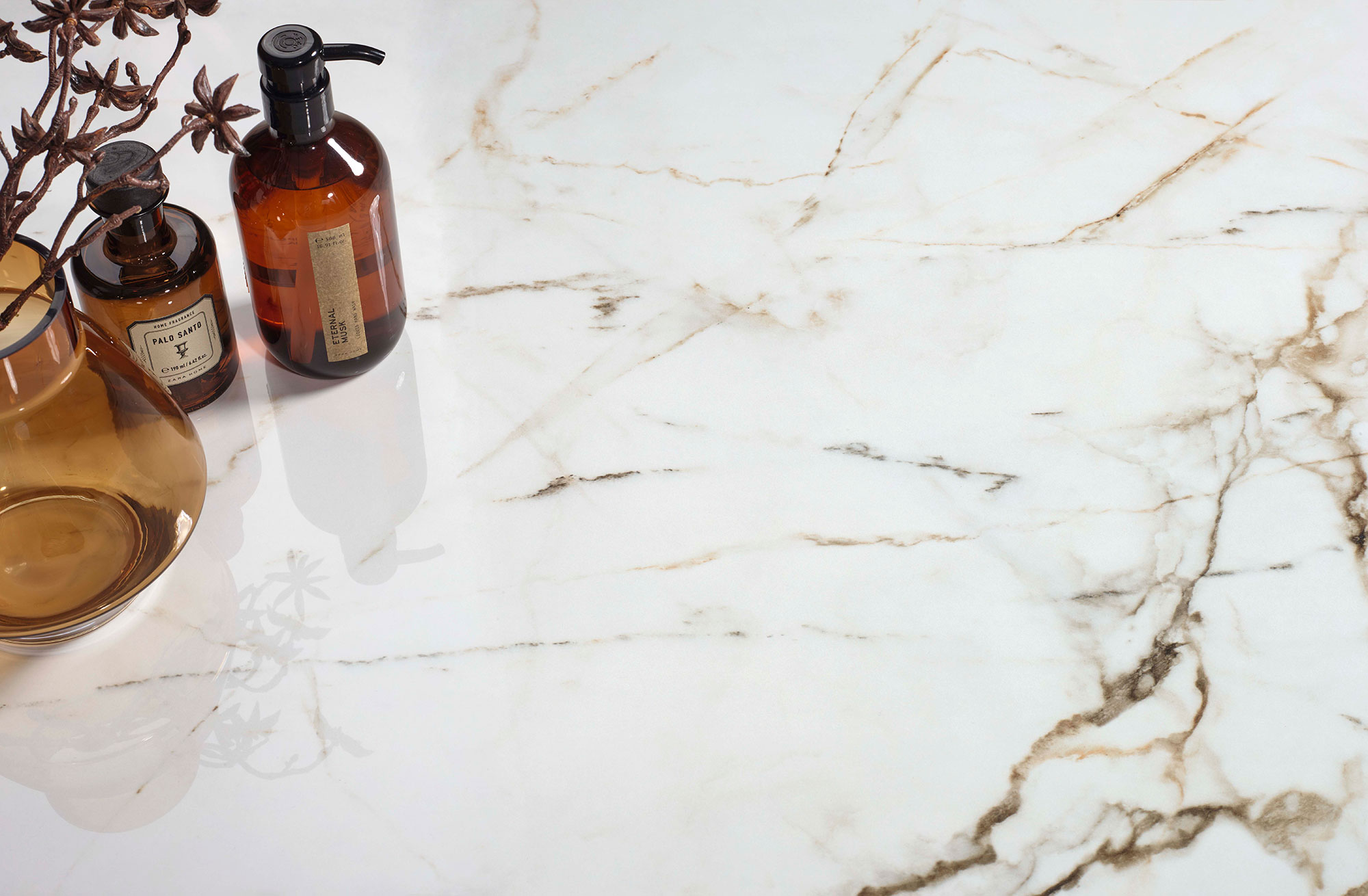 Encimera cerámica efecto mármol blanco con vetas marrones y frascos de vidrio ámbar