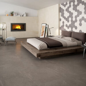 STN_AMB-BELLEVUE-WARM-60X120+75x75 Dormitorio moderno con pavimento gris, cama plataforma de madera, revestimiento hexagonal y chimenea