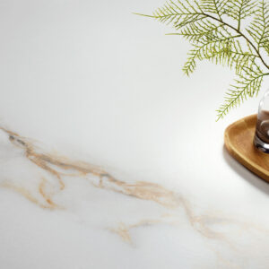 Baldosa cerámica blanca con vetas beige, jarrón de vidrio y bandeja de madera.