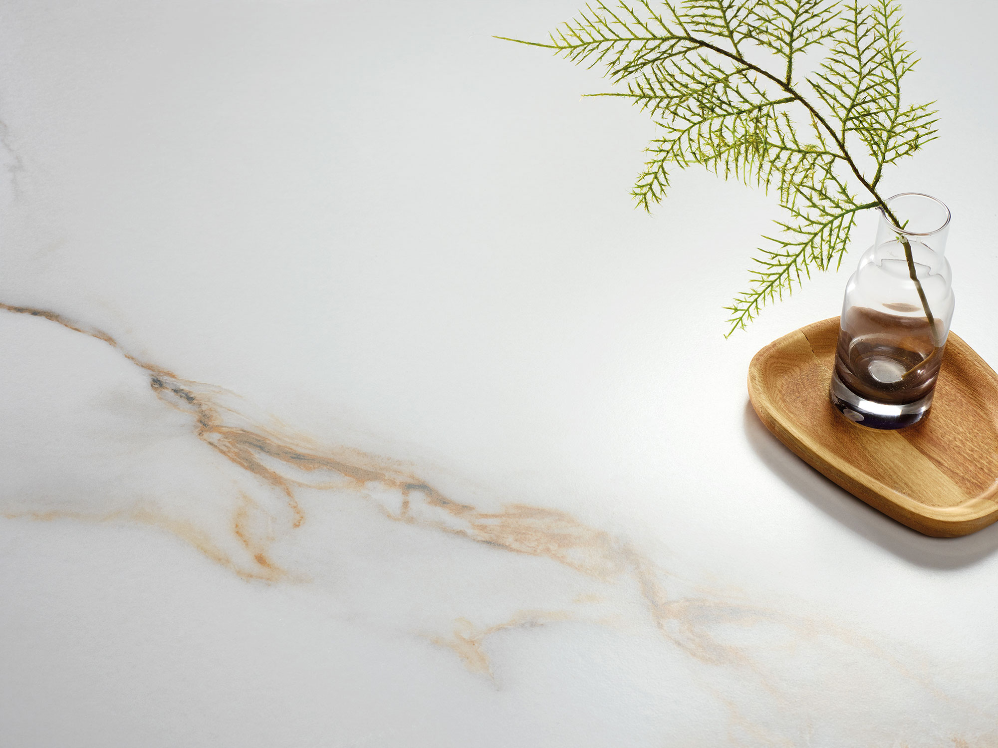 Baldosa cerámica blanca con vetas beige, jarrón de vidrio y bandeja de madera.