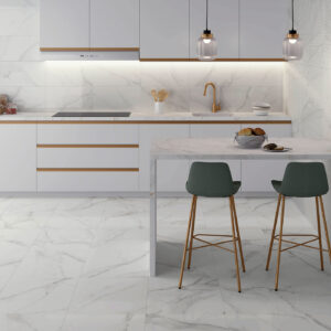 Cocina showroom con pavimento y revestimiento cerámico efecto mármol, encimera y taburetes.