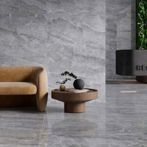 Showroom con azulejos grises efecto mármol, sofá camel, mesa de madera y recepción vegetal
