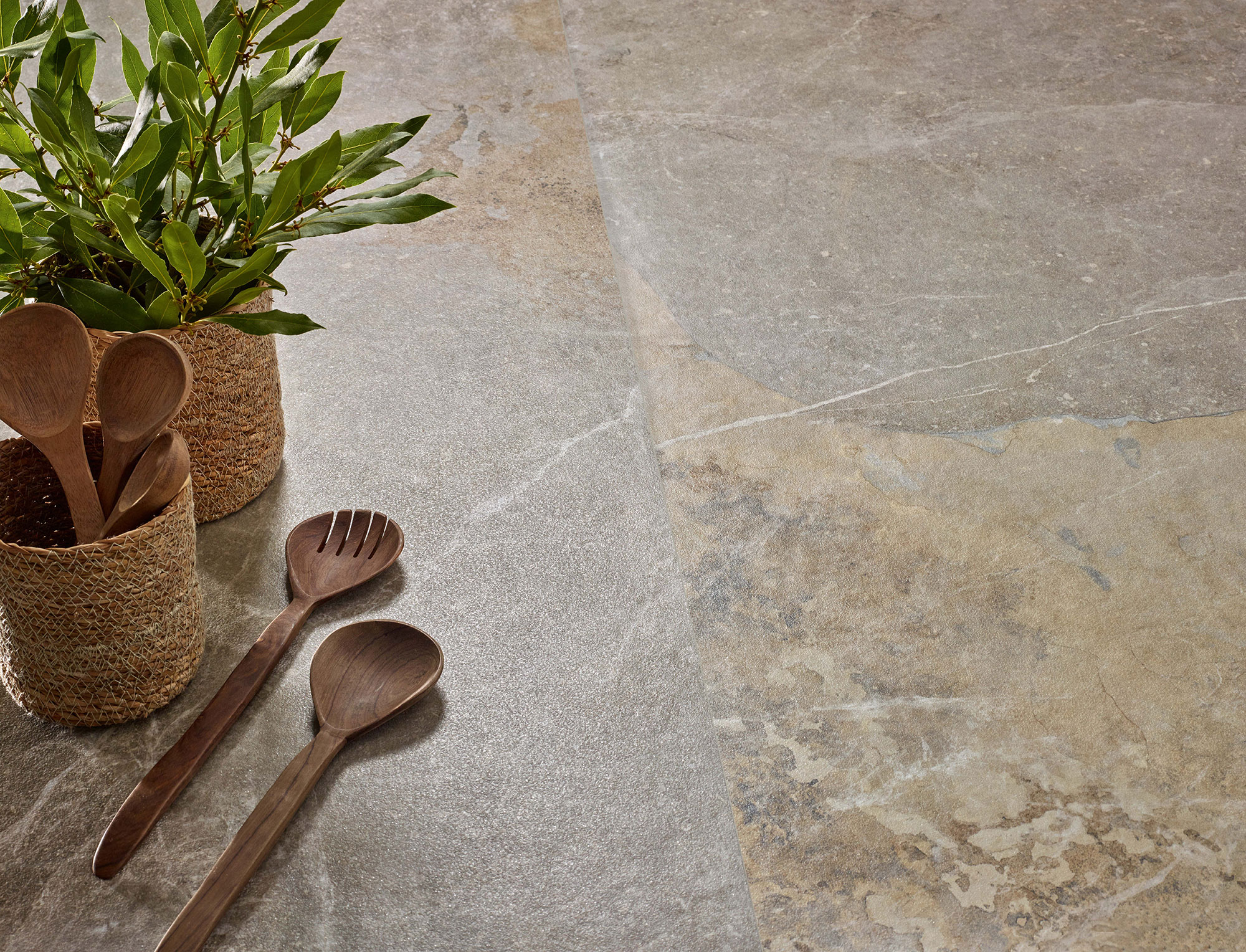 Azulejo cerámico efecto piedra gris-beige con cucharas de madera y cestas con hojas