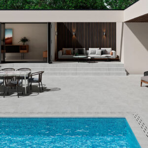 Patio con pavimento cerámico gris, piscina azul y zona de comedor y sofá