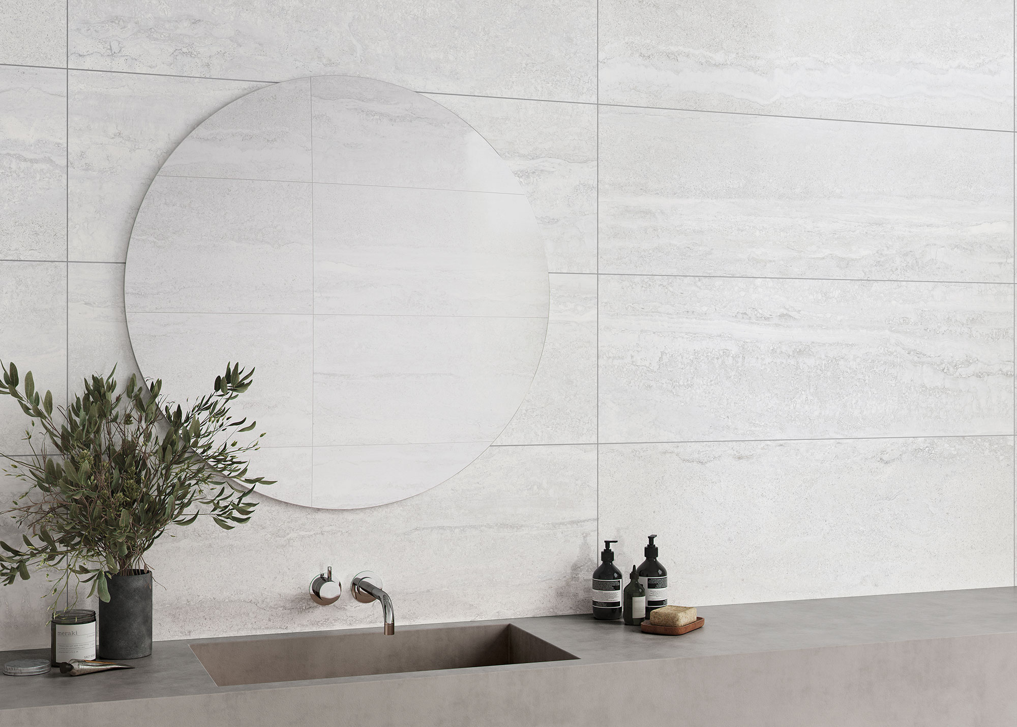 Baño minimalista con azulejos gris claro, espejo circular, lavabo, grifería y accesorios