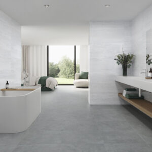 Baño de exposición con pavimentos y revestimientos cerámicos grises, bañera y lavabo doble.