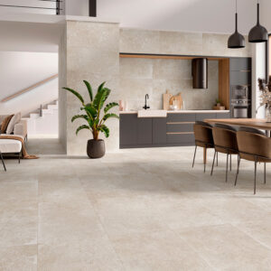 Salón y cocina abiertos con suelos revestidos, paredes cerámicas beige tipo piedra.