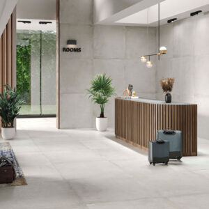 Recepción en tienda con suelos, paredes gran formato cerámico, mostrador listonado y plantas.