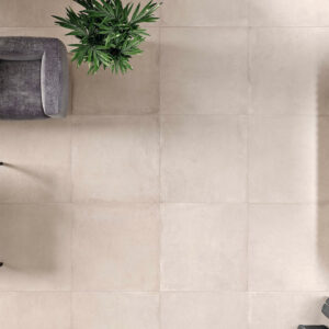 Salón visto desde arriba con pavimento cerámico beige, sofá gris, mesa de madera y planta.