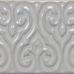 Azulejo cerámico brillante color crema con relieve ornamental en patrón repetido