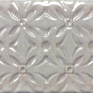 Azulejo cerámico brillante beige con relieve floral geométrico repetido