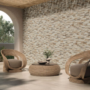 amb-ANDES-MIX_SWEDEN-HONEY_mq Terraza con revestimiento cerámico efecto piedra, pavimento claro y muebles de mimbre.
