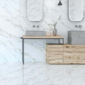 AMB-2-CALACATTA-GOLD Baño moderno con revestimiento y suelo efecto mármol, doble lavabo y mueble madera.