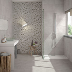 Baño de exposición con ducha, lavabo y revestimientos cerámicos grises y mosaico
