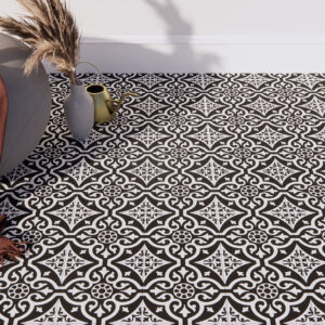 Pavimento cerámico negro y blanco con motivo geométrico vintage, puff y accesorios decorativos.