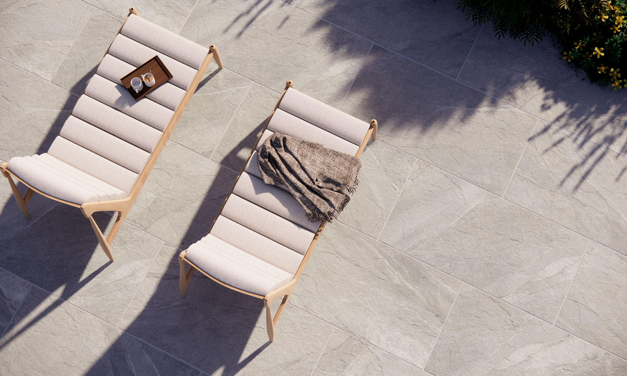 Tumbonas sobre pavimento cerámico gris efecto piedra, bandeja con tazas y manta