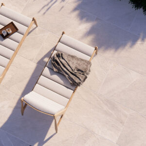 Tumbonas sobre pavimento cerámico efecto piedra beige con bandeja y manta