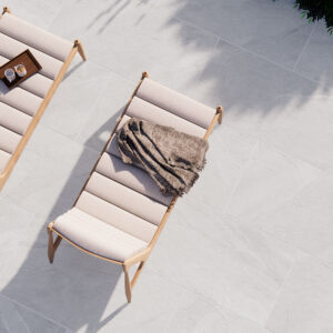 Dos tumbonas sobre pavimento cerámico gris efecto piedra con manta y bandeja