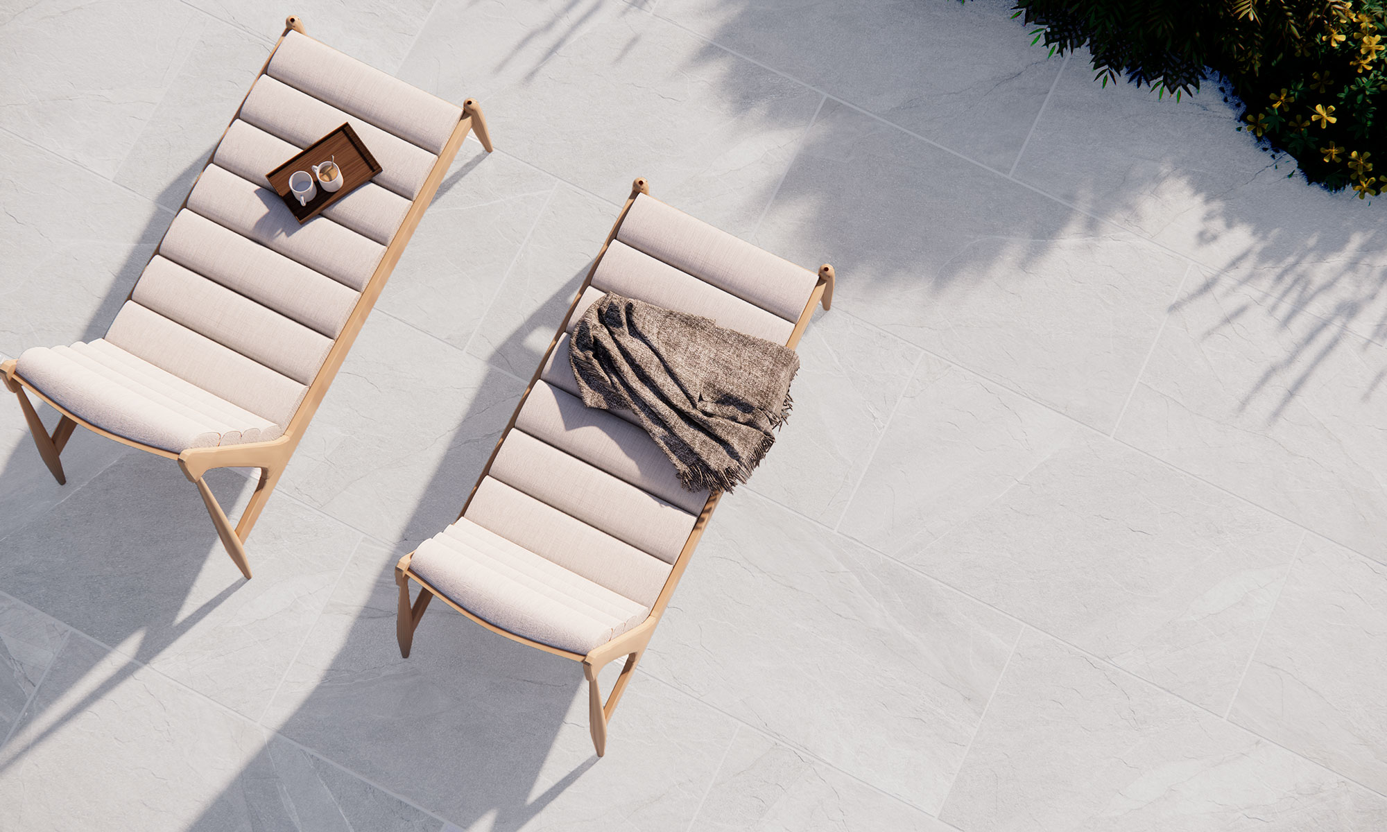 Dos tumbonas sobre pavimento cerámico gris efecto piedra con manta y bandeja