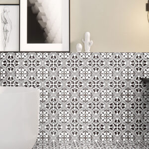 Ambiente de muestra con azulejos cerámicos blanco y negro, motivos geométricos, bañera y cuadros.