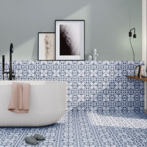 Baño con bañera blanca sobre azulejos cerámicos hidráulicos azul y blanco y grifería negra