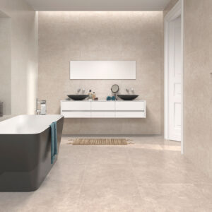 JPG-NUNKY-ARENA-MARRON__AMB Baño de exposición con bañera exenta gris, doble lavabo negro y azulejos beige mate