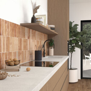 Cocina con azulejos rectangulares terracota, encimera clara y mobiliario de madera.