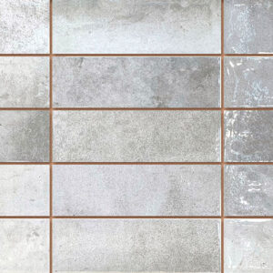 Azulejos cerámicos rectangulares grises con texturas mate y brillo, juntas marrón claro