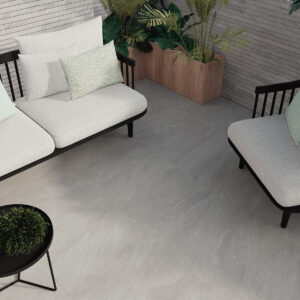 Terraza con pavimento cerámico gris efecto piedra, sofás claros y mesas negras