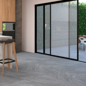 Cocina y terraza conectadas por puertas correderas sobre suelo cerámico gris efecto piedra