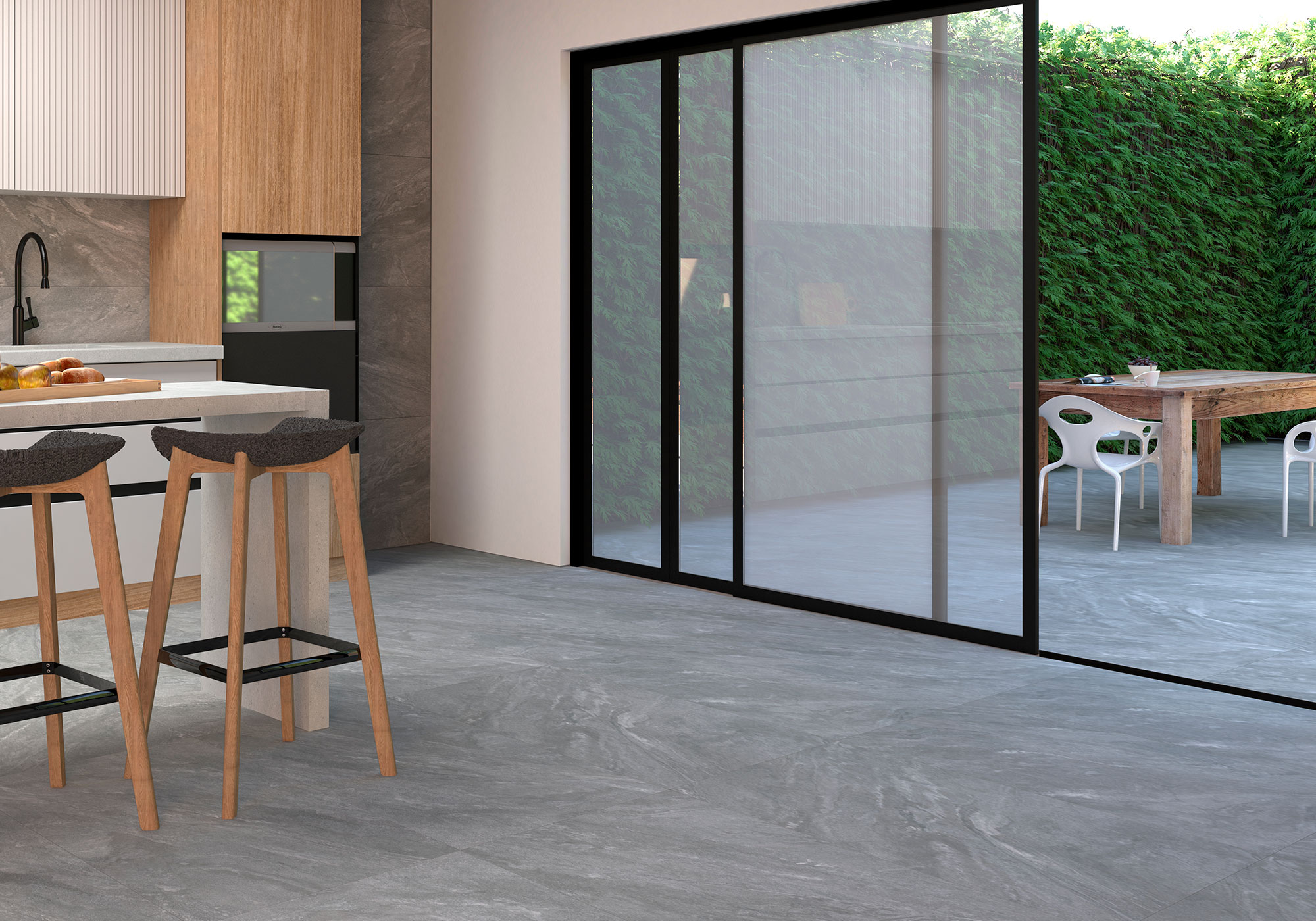 Cocina y terraza conectadas por puertas correderas sobre suelo cerámico gris efecto piedra