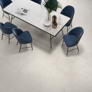 Mesa con tablero efecto mármol y sillas azules sobre pavimento cerámico beige