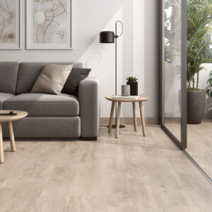 amb-02-galia-haya-20x75 Showroom con sofá gris y suelo cerámico imitación madera clara junto a terraza.