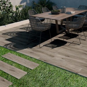 Patio con mesa y sillas sobre pavimento cerámico imitación madera y losetas en césped