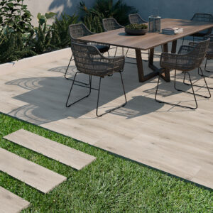 Patio exterior con pavimento cerámico efecto madera, mesa y sillas de comedor