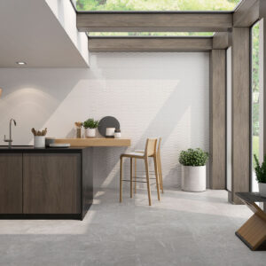 Ambiente de cocina en showroom con pavimento gris y revestimiento cerámico blanco texturado.