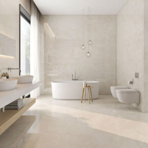 Baño moderno en showroom con azulejos crema pulidos, bañera exenta y lavabo doble.