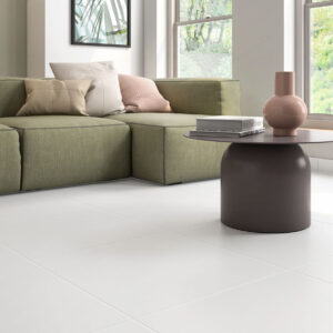 Suelo de grandes azulejos cerámicos blancos en salón moderno con sofá verde y mesa baja